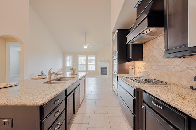 kitchen featuring ceiling fan, tasteful backsplash, custom exhaust hood, a sink, and stainless steel appliances