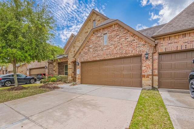 view of front of property with driveway, a garage, stone siding, and brick siding