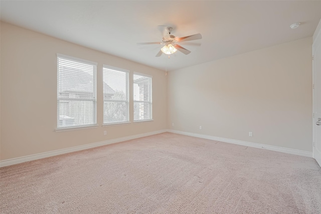 spare room featuring baseboards, light colored carpet, and ceiling fan