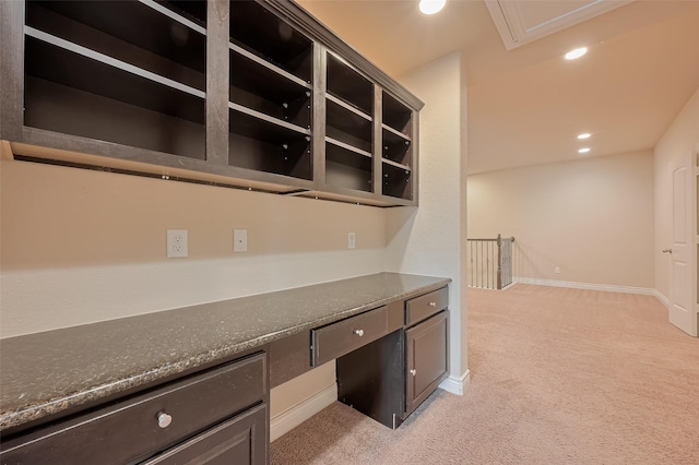 unfurnished office featuring built in desk, baseboards, recessed lighting, and light carpet