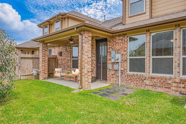 rear view of house featuring ceiling fan, a lawn, fence, a patio, and brick siding