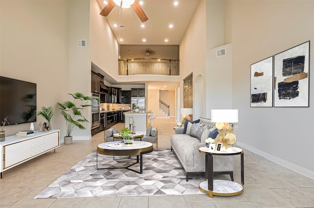 living room featuring light tile patterned floors, visible vents, baseboards, and ceiling fan