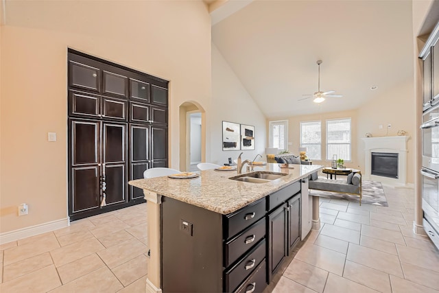 kitchen with arched walkways, light tile patterned floors, a sink, and ceiling fan