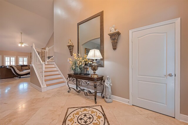 entrance foyer featuring tile patterned flooring, high vaulted ceiling, a ceiling fan, baseboards, and stairway