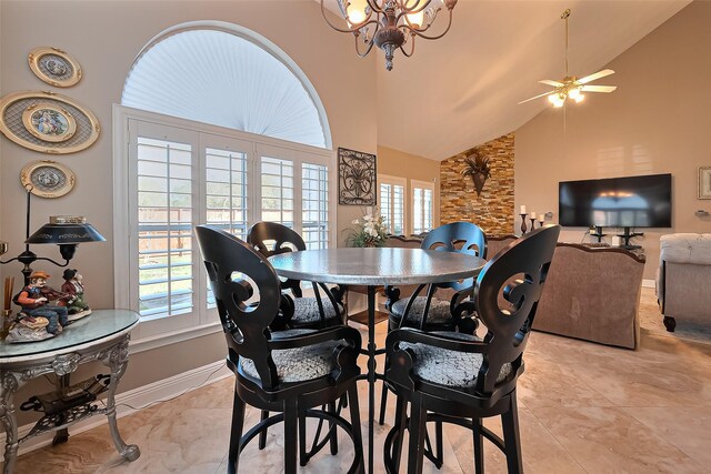 dining space featuring light tile patterned flooring, high vaulted ceiling, baseboards, and ceiling fan with notable chandelier