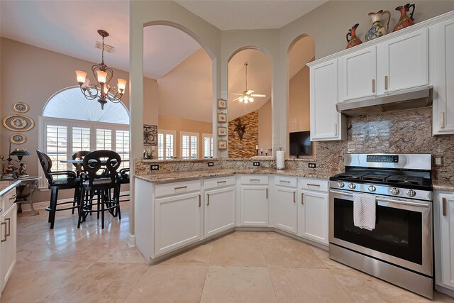 kitchen featuring under cabinet range hood, light stone counters, decorative backsplash, and stainless steel gas stove