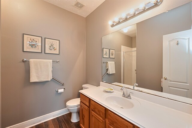 bathroom featuring visible vents, a shower with shower door, wood finished floors, vanity, and toilet