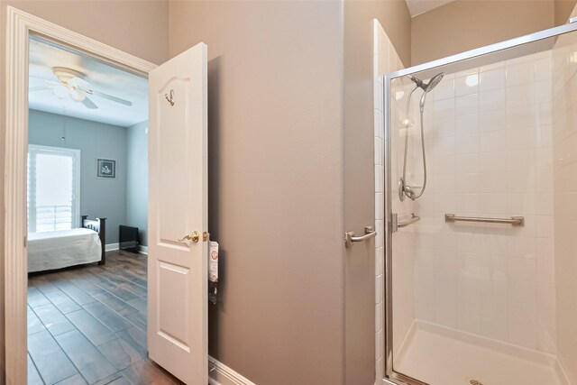 bathroom with a ceiling fan, baseboards, a shower stall, and ensuite bathroom