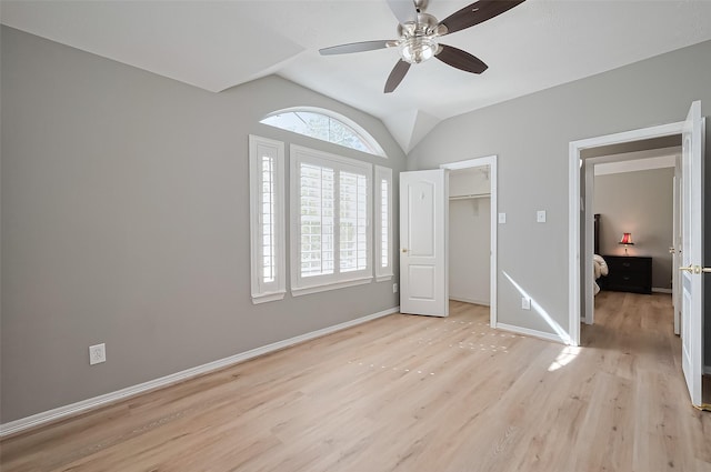 unfurnished bedroom featuring a closet, lofted ceiling, light wood-style floors, baseboards, and ceiling fan