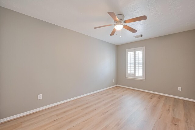 unfurnished room featuring a ceiling fan, baseboards, visible vents, and light wood-style flooring