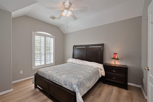 bedroom with ceiling fan, visible vents, vaulted ceiling, baseboards, and light wood-style flooring