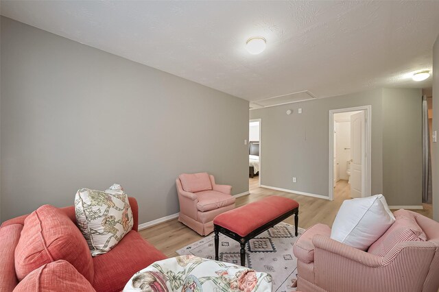 living room with baseboards, attic access, and light wood-style floors