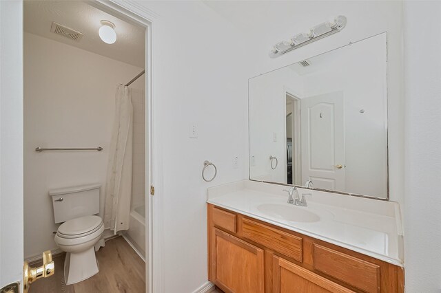 full bathroom featuring visible vents, shower / tub combo with curtain, vanity, wood finished floors, and toilet