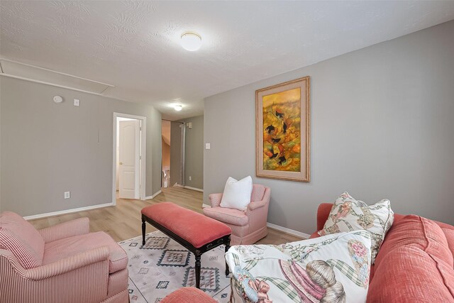 living area with baseboards, attic access, and light wood-style floors