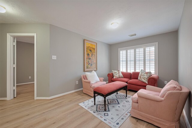 living room with baseboards, light wood finished floors, and visible vents