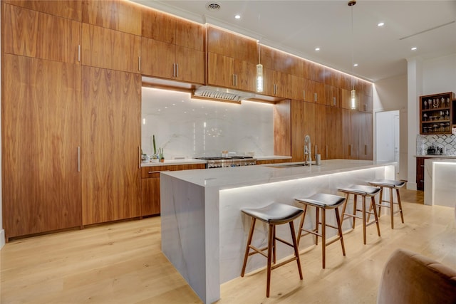 1810 Dunlavy St, Houston, TX 77006 - kitchen with a sink, tasteful backsplash, light wood finished floors, a breakfast bar, and light countertops