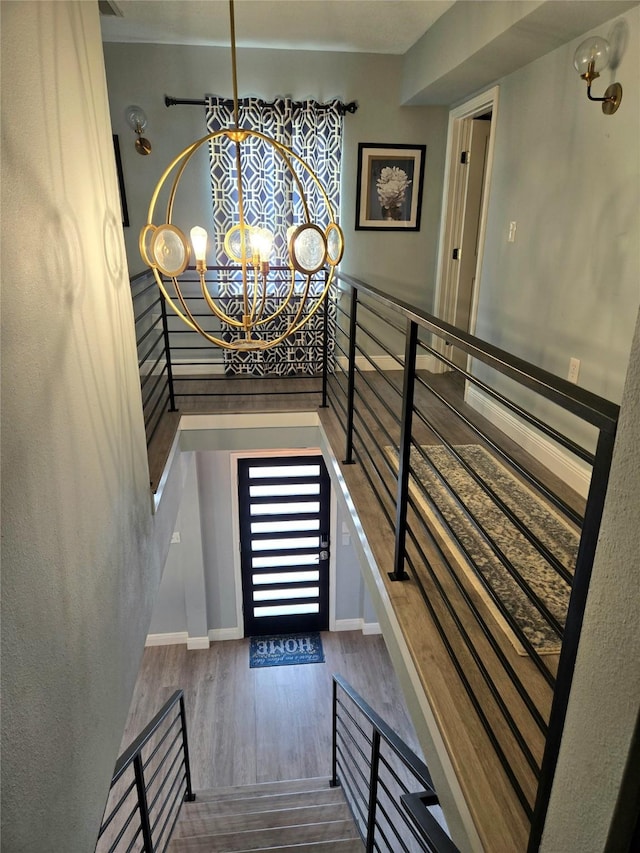 staircase featuring a chandelier, wood finished floors, and baseboards