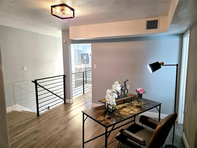 dining space featuring wood finished floors, baseboards, and a textured ceiling