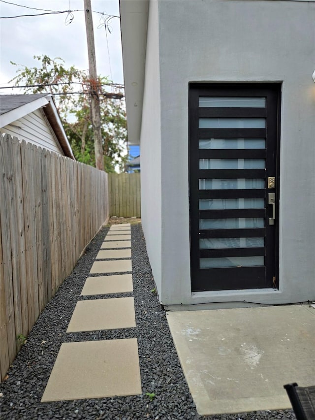 view of side of home with fence and stucco siding