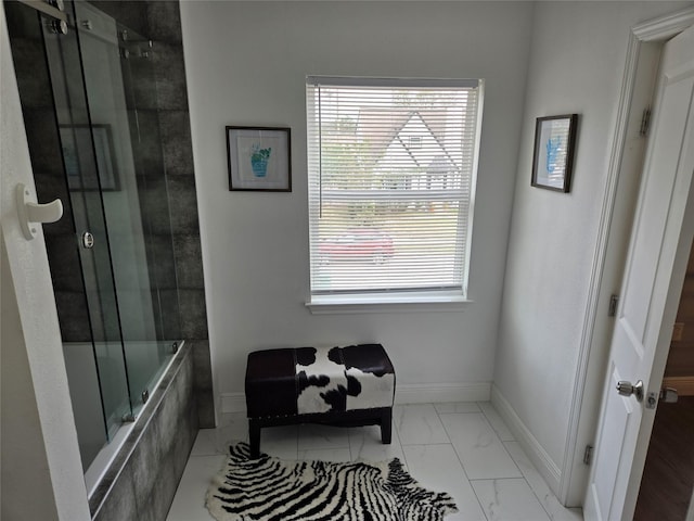 bathroom with marble finish flooring, baseboards, and tiled shower / bath