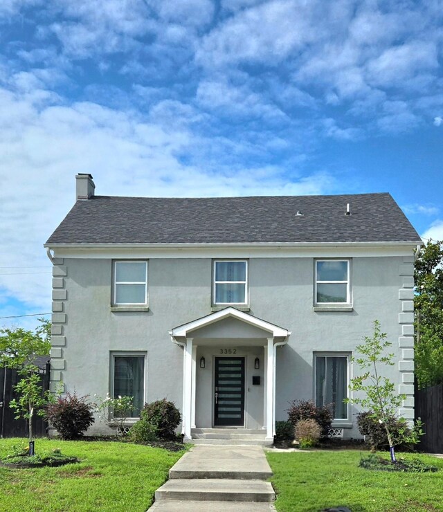 view of front of house with stucco siding and a chimney