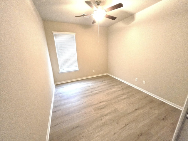 empty room featuring a ceiling fan, wood finished floors, and baseboards