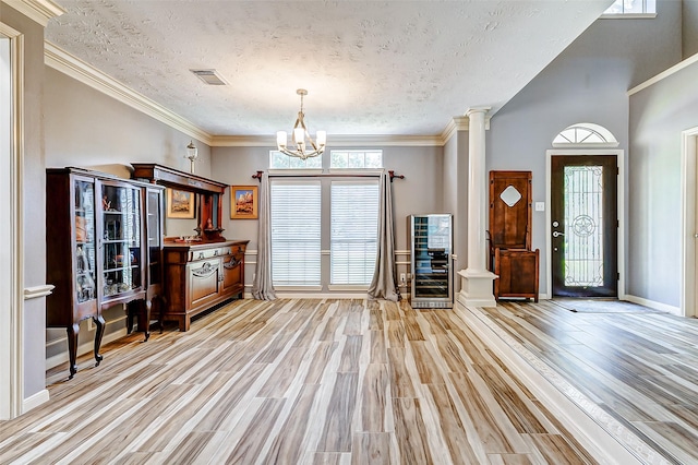 entryway with light wood-style floors, visible vents, a textured ceiling, and a chandelier