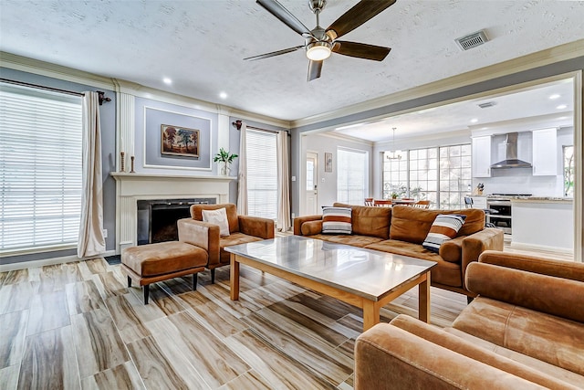 living area featuring ornamental molding, recessed lighting, a ceiling fan, visible vents, and a premium fireplace
