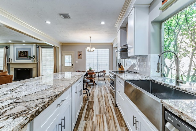 kitchen featuring white cabinetry, visible vents, appliances with stainless steel finishes, a sink, and a notable chandelier