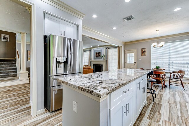 kitchen featuring visible vents, light stone counters, stainless steel refrigerator with ice dispenser, and light wood-style floors