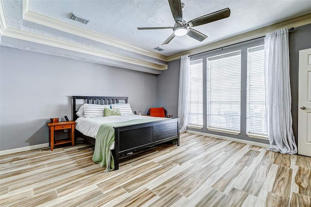 bedroom with baseboards, ornamental molding, a ceiling fan, visible vents, and wood finished floors