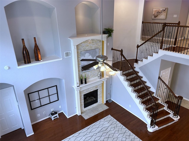 11603 Shoal Landing St, Pearland, TX 77584 - living room with wood finished floors, a ceiling fan, a fireplace with flush hearth, a high ceiling, and stairs
