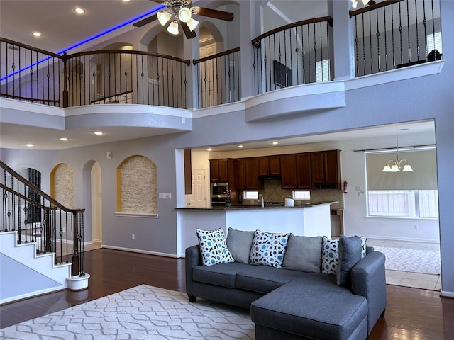 11603 Shoal Landing St, Pearland, TX 77584 - living area featuring dark wood-type flooring, ceiling fan, a chandelier, baseboards, and a high ceiling