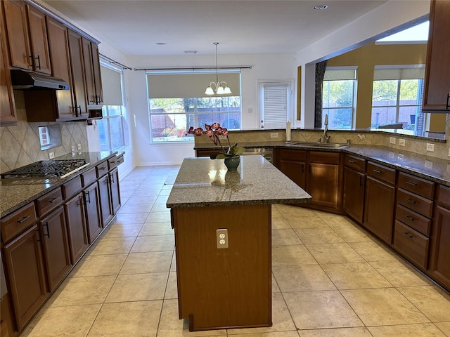 11603 Shoal Landing St, Pearland, TX 77584 - kitchen featuring a sink, under cabinet range hood, a kitchen island, dark stone counters, and stainless steel gas cooktop