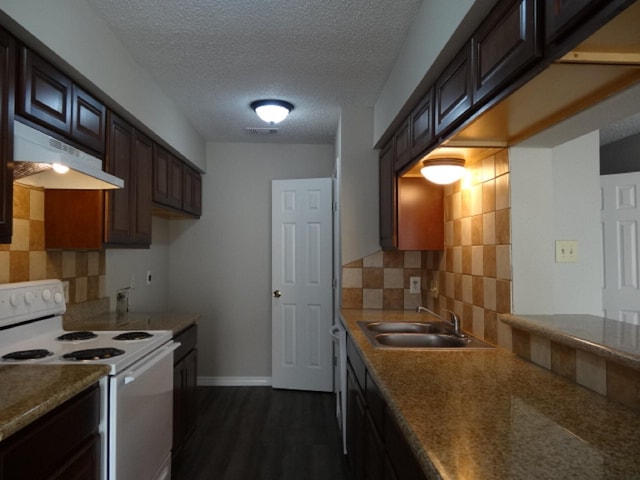 kitchen featuring visible vents, white electric range, under cabinet range hood, a sink, and dark wood-style floors