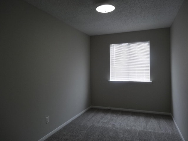 carpeted empty room featuring baseboards and a textured ceiling