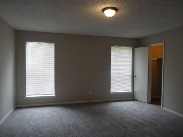 spare room featuring carpet floors, baseboards, and a textured ceiling