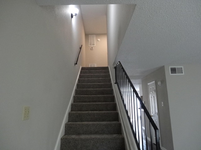 stairway with baseboards and visible vents