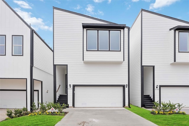 contemporary house with a front yard, concrete driveway, stairway, and an attached garage
