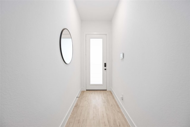doorway to outside with baseboards and light wood-style flooring