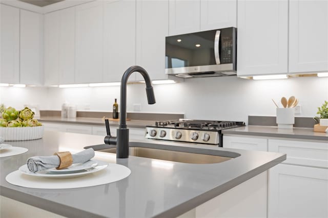 kitchen with stainless steel microwave, a sink, and white cabinetry
