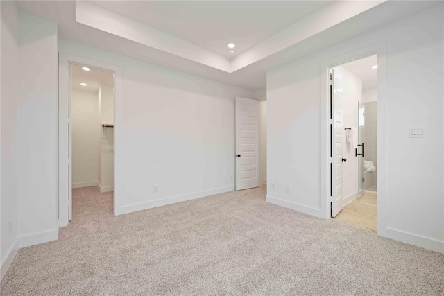 interior space featuring carpet flooring, a tray ceiling, baseboards, and recessed lighting