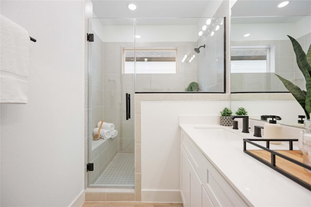bathroom featuring a stall shower, baseboards, and vanity