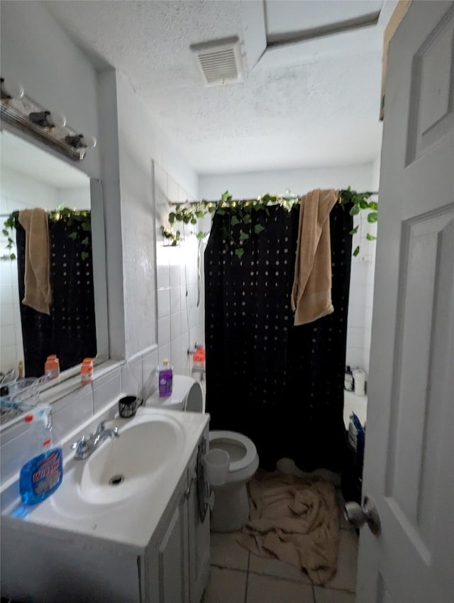 706 66th St Unit 2, Houston, TX 77011 - full bathroom featuring toilet, vanity, a textured ceiling, visible vents, and tile walls
