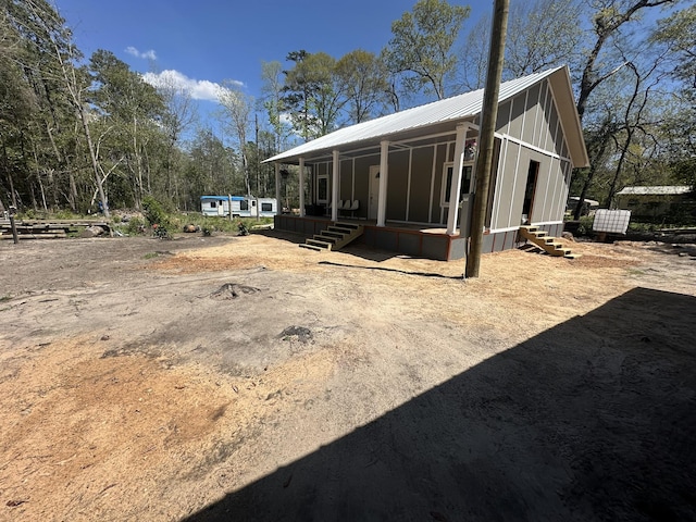 rear view of house with metal roof, covered porch, and board and batten siding