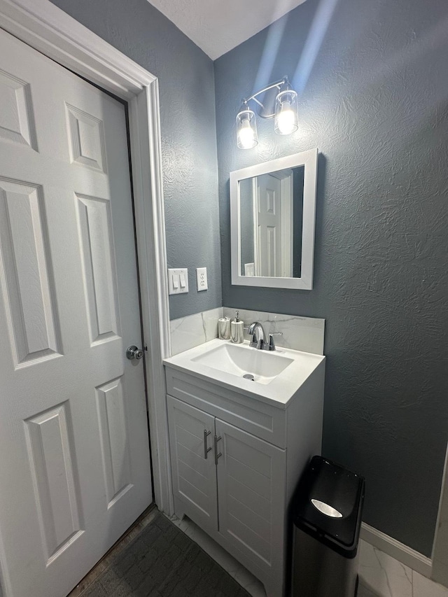 bathroom featuring marble finish floor, vanity, and a textured wall