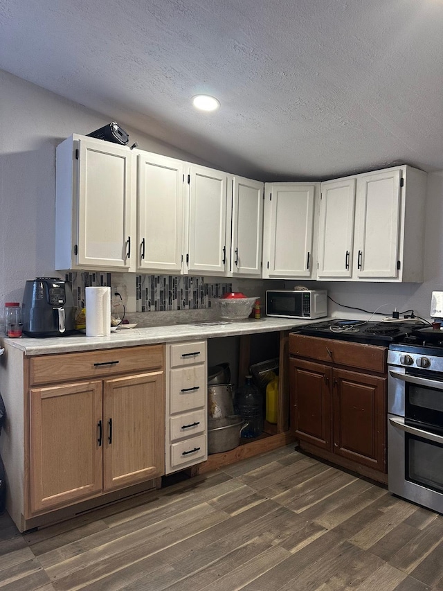 kitchen featuring dark wood-style floors, white cabinetry, range with two ovens, and a textured ceiling
