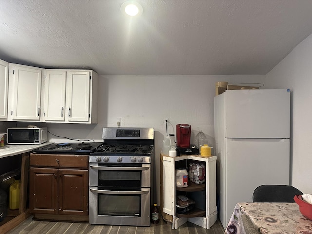 kitchen featuring light countertops, freestanding refrigerator, double oven range, white cabinetry, and dark wood-type flooring