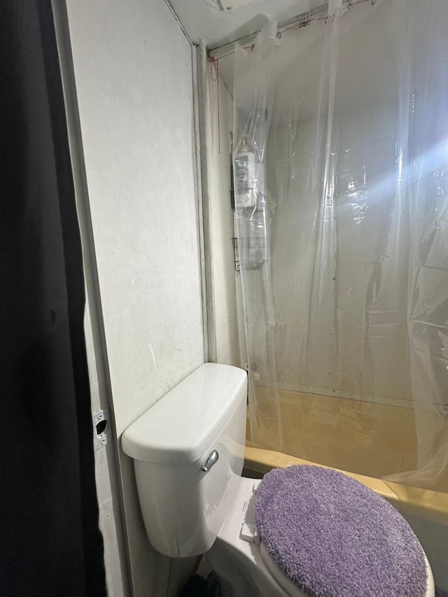 bathroom featuring toilet and curtained shower