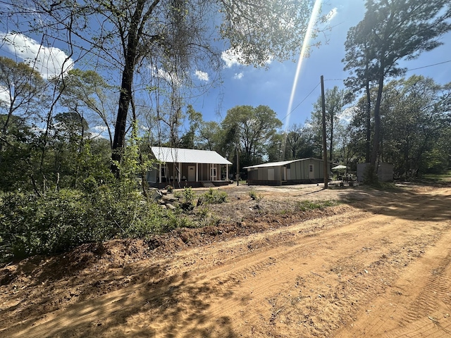 view of yard featuring dirt driveway, covered porch, and an outdoor structure